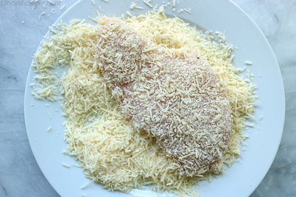 Cheese coated chicken breast on a plate.
