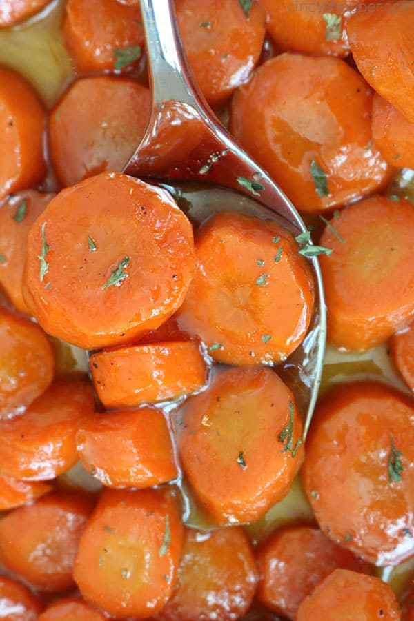 Glazed Carrots on a spoon, inside of a pan.