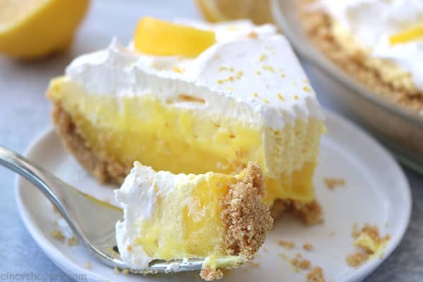 Fork filled with lemon pie on plate.