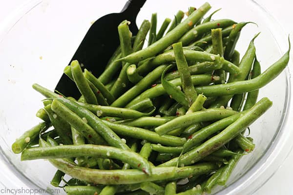 Tossing garlic green beans in a bowl.