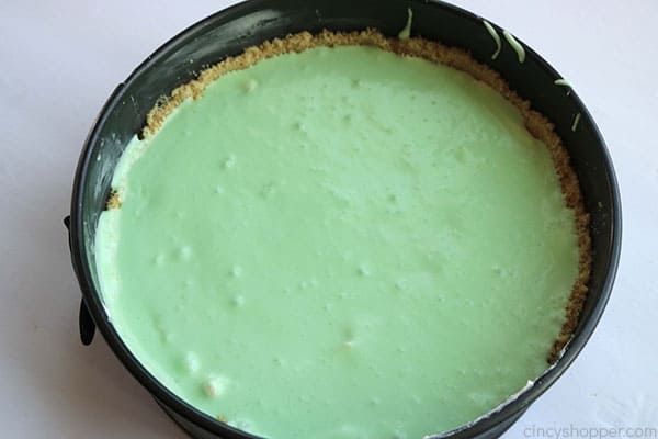 Adding lime cream cheese mixture to crust for lime cheesecake.