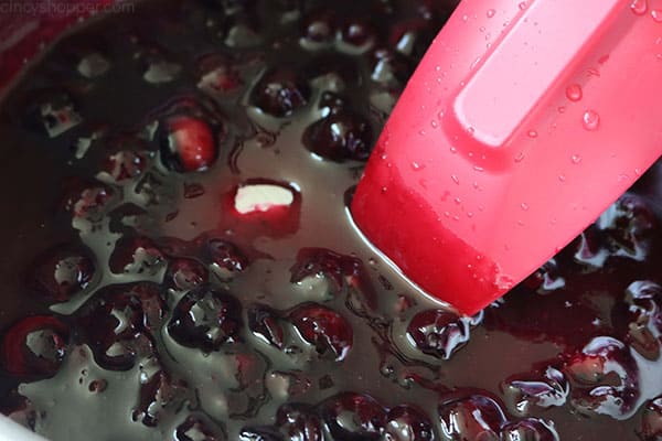 Stirring easy blueberry sauce in a pan.