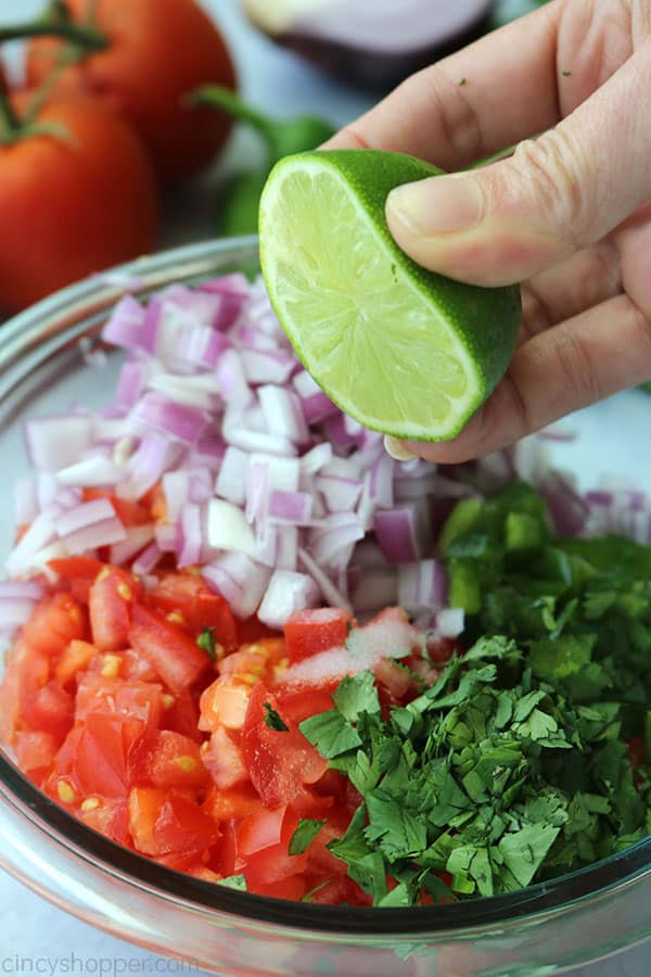Squeezing lime juice on top of Pico de Gallo ingredients.