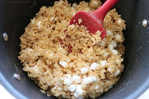 Adding Rice Krispie Cereal to pan for treats.