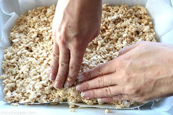 Pressing Rice Krispie mixture into pan.