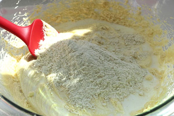 Slowly adding dry ingredients to banana cake batter.