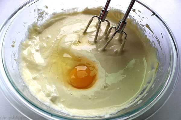 Adding eggs to cream cheese mixture for Caramel Apple Cheesecake Bars.