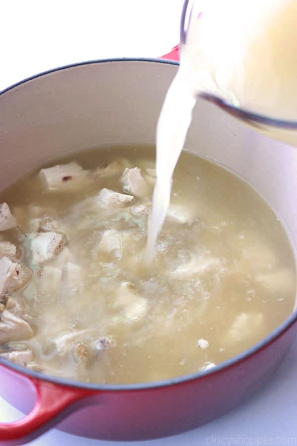 Adding broth to chicken creamy soup.