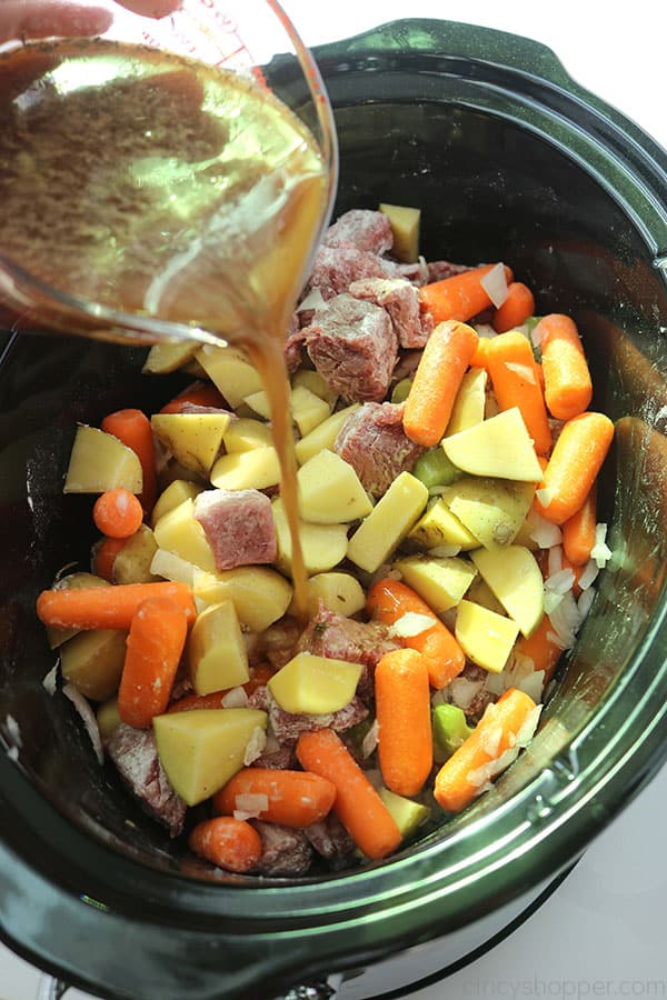 Gravy mixture pouring over vegetables and meat.