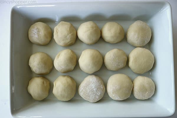 Unbaked dinner rolls in a white baking dish.