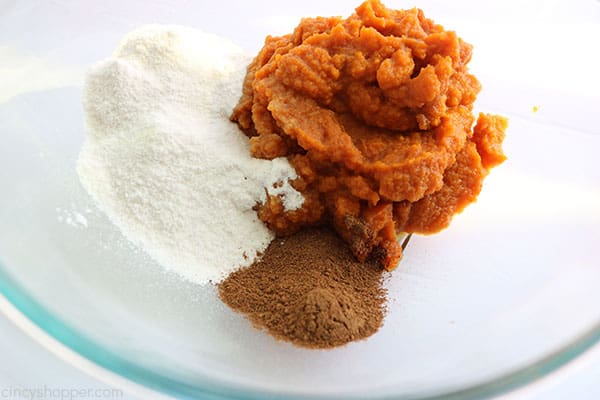 Pumpkin, vanilla pudding mix and pumpkin pie spice in a bowl.