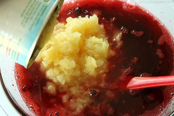 Adding crushed pineapple to Jello mixture.