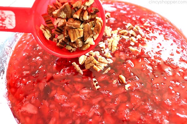 Adding crushed pecan nuts to Cranberry Jello Salad.