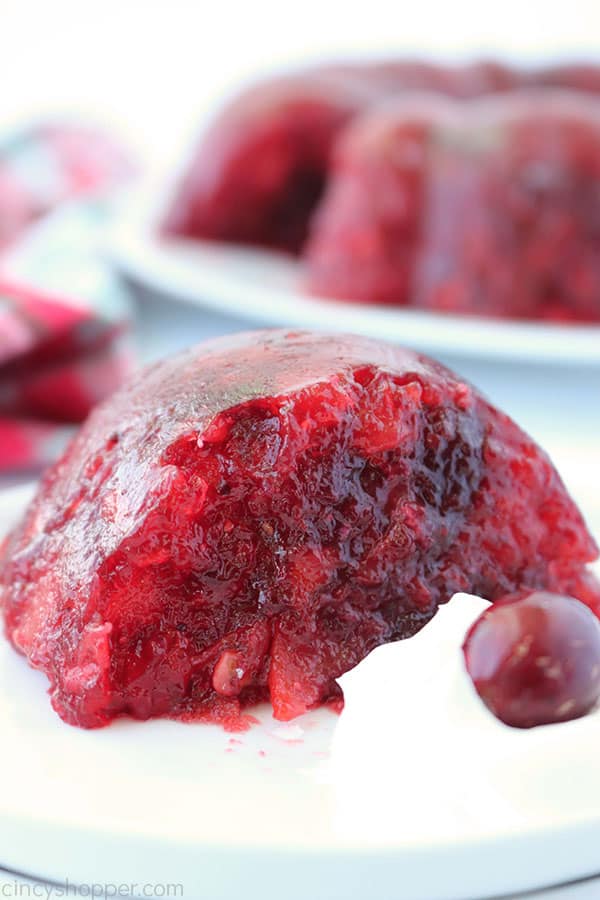 Slice of Cranberry Salad on a plate with whipped topping and a fresh cranberry.