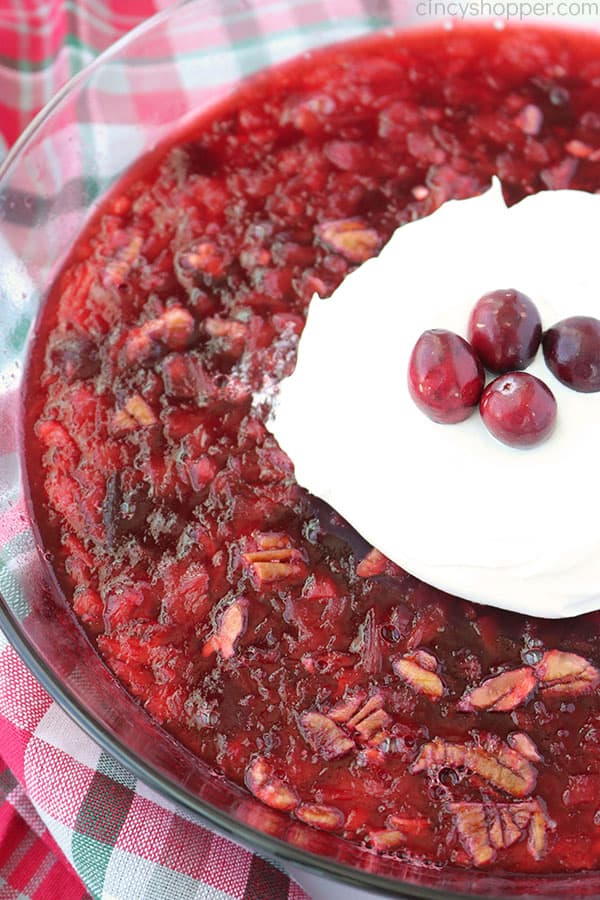 Old Fashioned Cranberry Salad in a clear bowl with whipped cream and fresh cranberries.