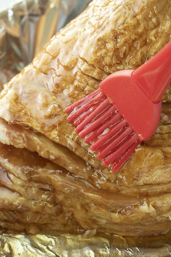 Coating Honey Baked Ham with raw honey for delicious flavor.