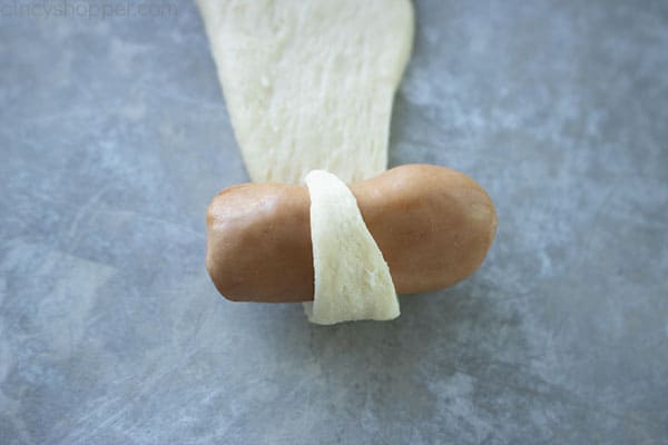 Rolling mini hot dog in crescent dough