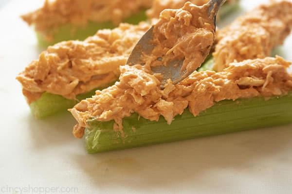 spooning Buffalo chicken onto ribs of celery