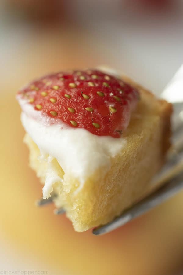 close up of a bite of moist pound cake recipe on a fork with whipped cream and strawberry