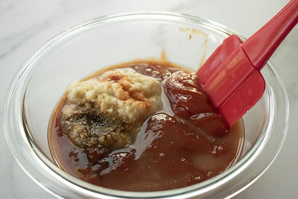 ingredients in a glass bowl being stirred a a spatula