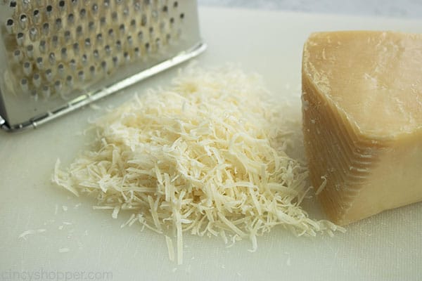 Parmesan cheese block with grater and a small pile of grated cheese