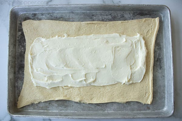 layer of cream cheese spread onto pastry dough on a sheet pan