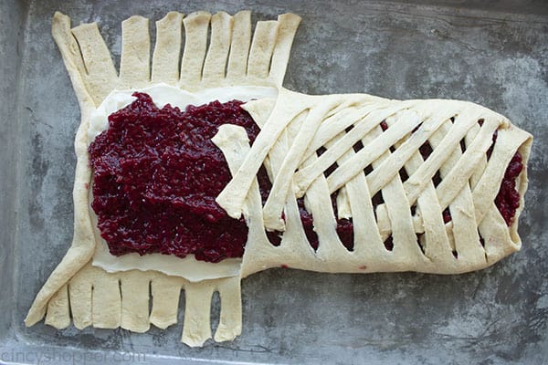 braiding crescent roll dough over cream cheese and raspberry filling