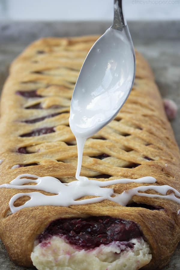 spooning sweet icing over braided pastry dessert