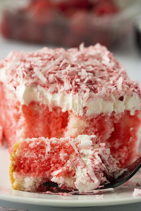 Raspberry and coconut poke cake slice with a fork