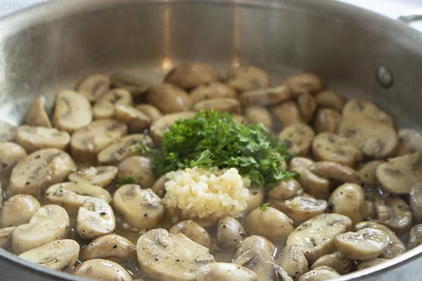 mushrooms cooking in skillet with butter, garlic, and parsley