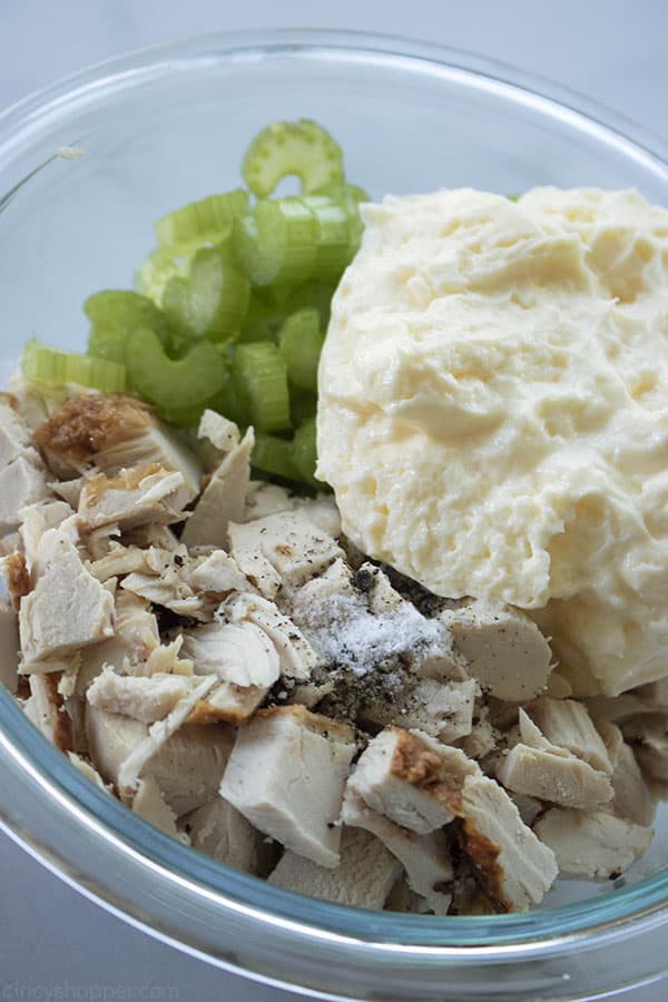 chunks of cooked chicken, chopped celery, and mayo in a glass bowl