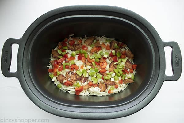 layers of shredded potatoes, bacon, and vegetables in crock pot