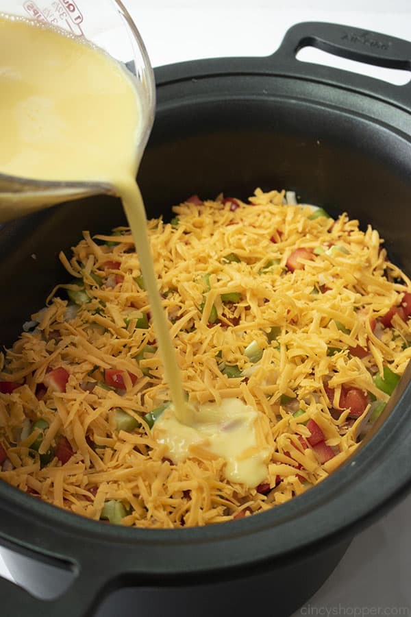 pouring whisked eggs into crock pot to make hashbrown casserole