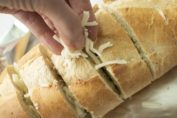 stuffing shredded cheese inside of a loaf of French bread