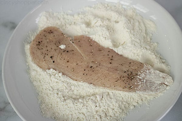 dredging raw chicken through flour