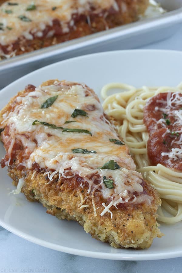 breaded chicken breast smothered with cheese next to spaghetti