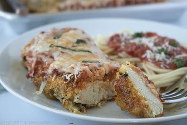 piece of chicken parm on a fork next to plate with the Italian comfort food