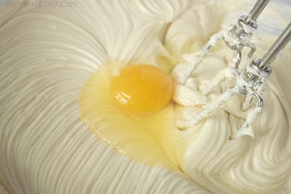 adding eggs to cheesecake filling