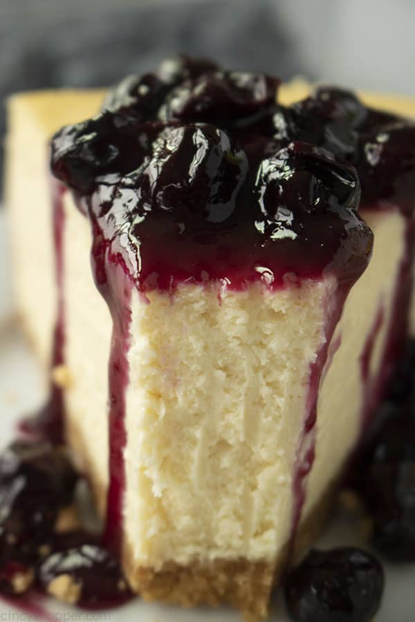 close up photo of creamy ny style cheesecake with blueberry sauce