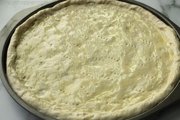 unbaked pizza dough on a circular pizza pan
