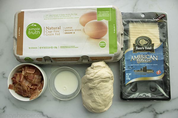 ingredients on counter to make a pizza recipe: pizza dough, bacon, eggs, and American cheese