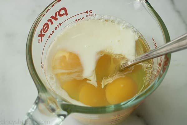 whisking eggs and milk together in a glass measuring cup