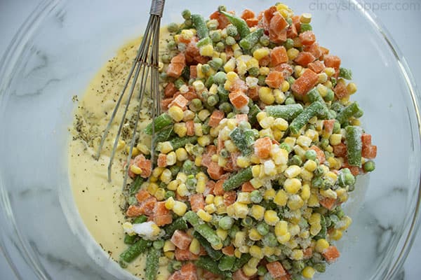 whisking frozen peas, corn, carrots, and green beans into soup mixture