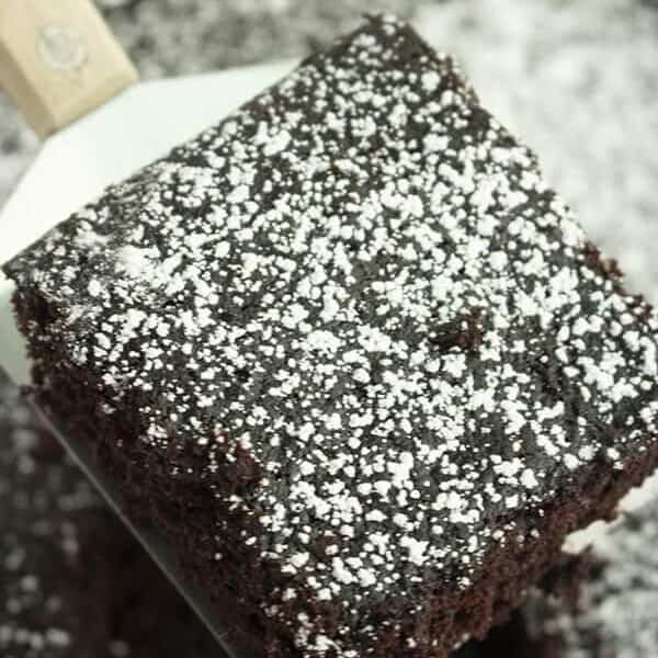 square slice of wacky chocolate cake dusted with powdered sugar