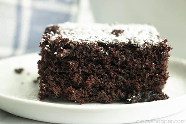 slice of chocolate cake with powdered sugar on top, sitting on a plate