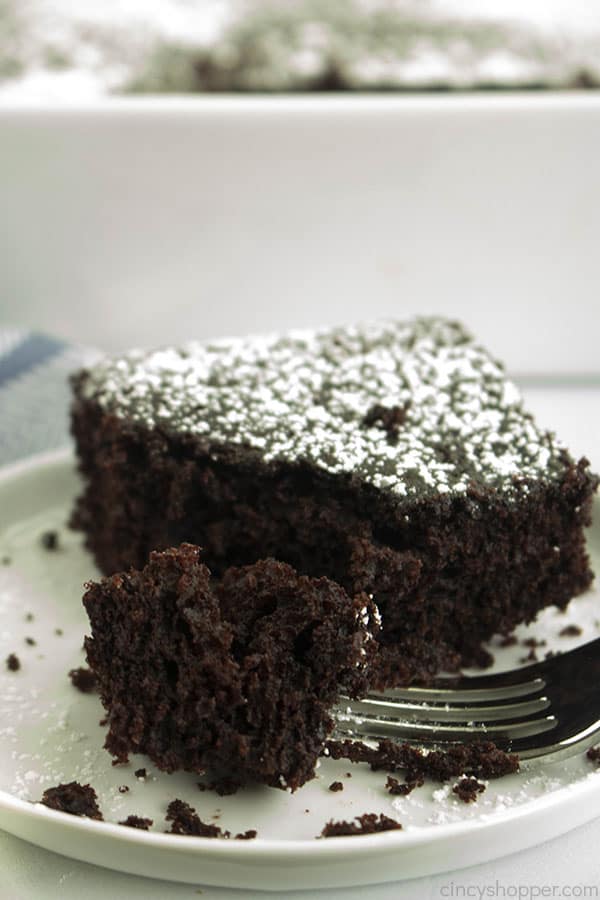 slice of rich chocolate cake on a plate, with piece on a fork