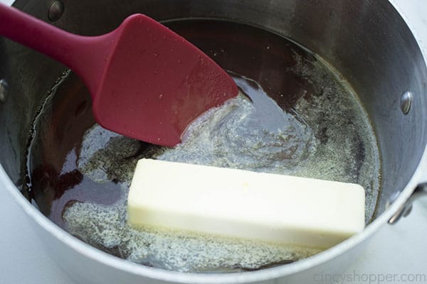 Making homemade syrup recipe, adding butter to the pan.