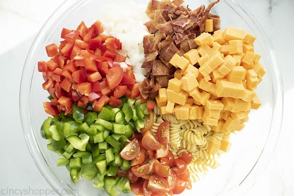 Pasta, bacon and veggies in a large bowl to make pasta salad