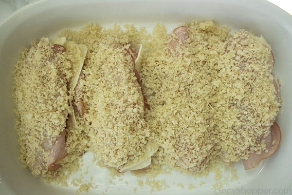 stuffed chicken breasts covered in breadcrumbs inside a baking dish