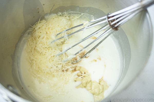 metal whisk combining cheese and mustard with cream sauce